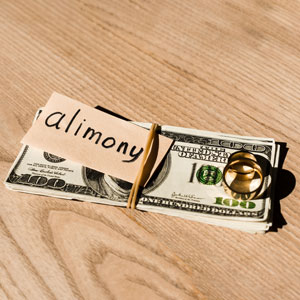 Money and wedding rings on a wooden table, with the word 