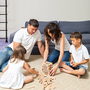 A family of four plays a block-stacking game on the floor Represent Domestic Violence