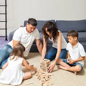 A family of four plays a block-stacking game on the floor Represent Domestic Violence